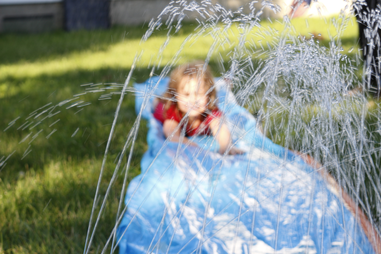 A child playing on a water slide in the garden